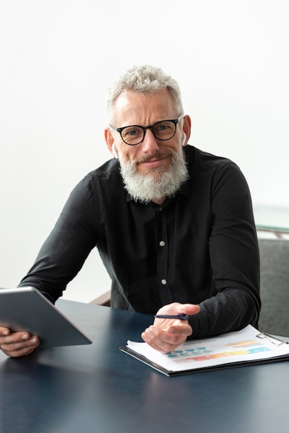 Senior man with glasses at home studying while using tablet