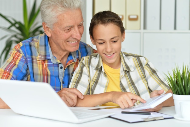 Senior man with grandson using laptop at home