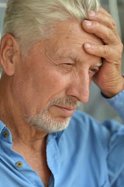 Senior man with headache holding hand on head