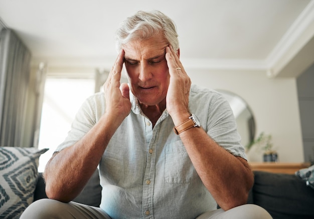 Senior man with headache stress or anxiety about retirement financial problem or house mortgage in his living room Sick elderly man with migraine pain or mental health risk and frustrated on sofa