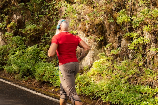 Senior man with white beard doing running outdoor on the nature