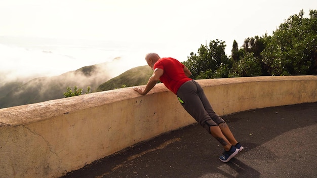 Senior man with white beard doing sport exercises outdoor