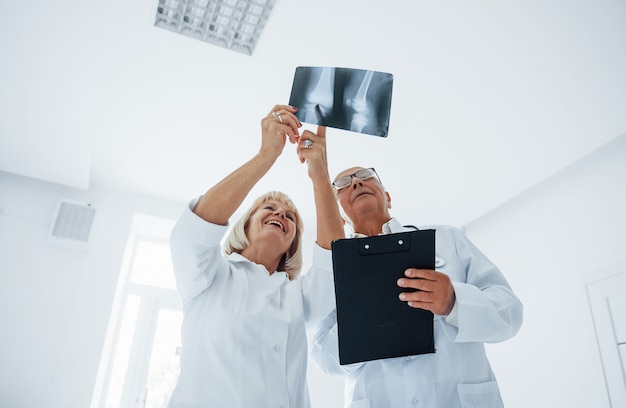 Senior man and woman doctors in white uniform examines x-ray of human legs.