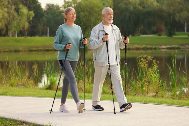 Photo senior man and woman performing nordic walking outdoors