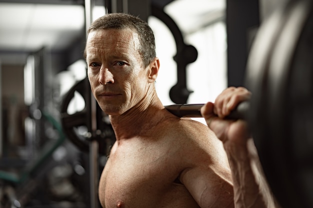 Senior man working out at the gym doing squats