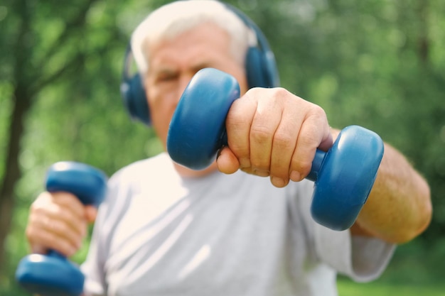 Foto uomo anziano che fa esercizio all'aperto persona che solleva manubri uomo vecchio che si esercita nel parco stile di vita di persone sane allenamento sportivo attivo sportivo anziano anziano che face esercizio fisico sessione di allenamento