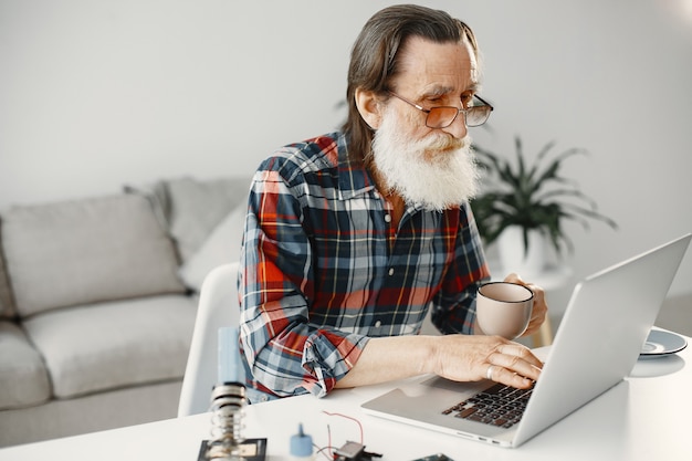 Старший мужчина, работающий с ноутбуком в гостиной