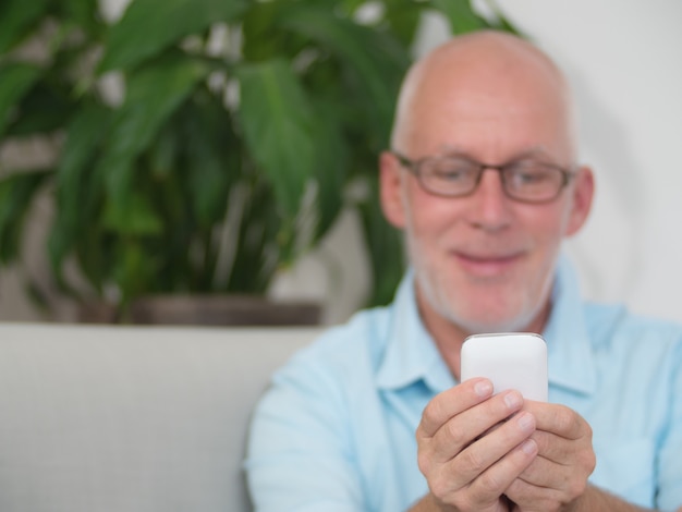 Senior man writing message on smartphone