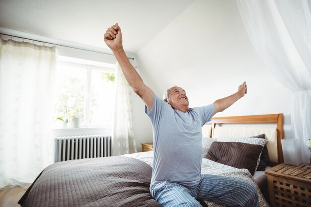 Senior man yawning on bed