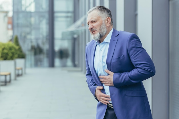 Foto senior man zakenman kantoormedewerker in een pak staat in de buurt van het kantoorcentrum op straat