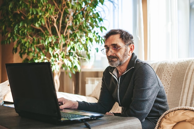 Senior man zit voor de laptop