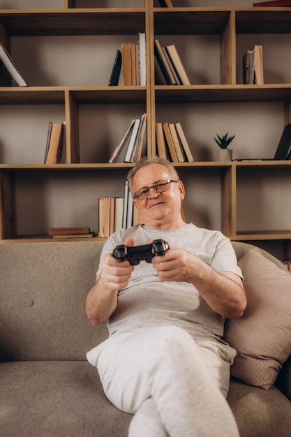 Senior man zittend op een bank en het spelen van een videogame