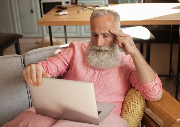 Senior man zittend op een bank voor een laptopcomputer