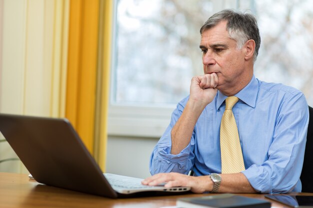 Senior manager at work on his laptop in his office