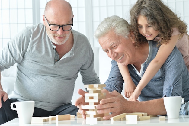 Senior mannen en kleindochter die plezier hebben en thuis een bordspel spelen