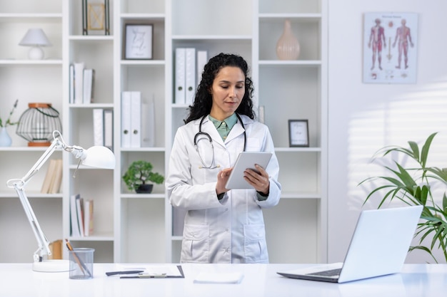 Senior mature female doctor serious and confident thoughtfully using tablet computer latin american