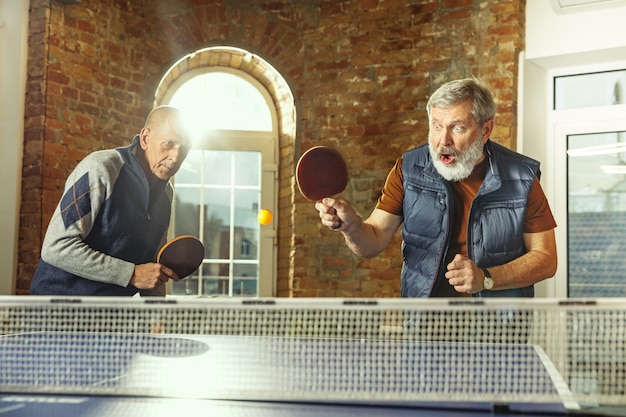 Photo senior men playing table tennis in workplace having fun