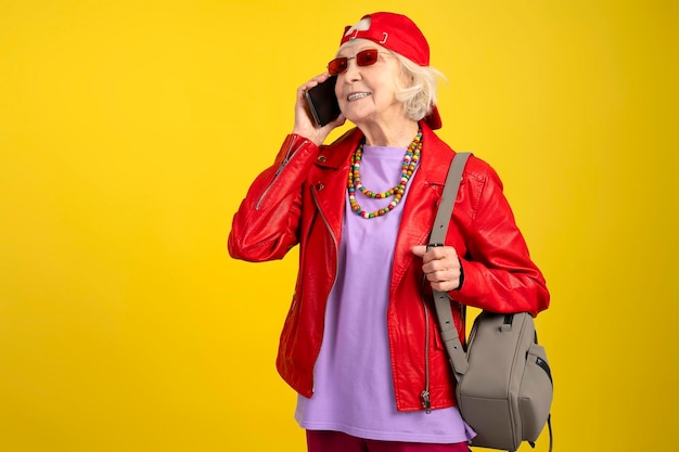 Senior modern urban caucasian woman with backpack talking on mobile phone