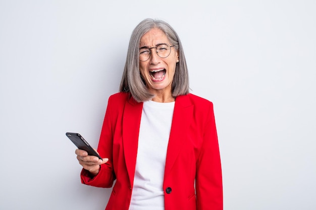 Senior mooie vrouw die agressief schreeuwt en er erg boos uitziet, zaken en telefoonconcept