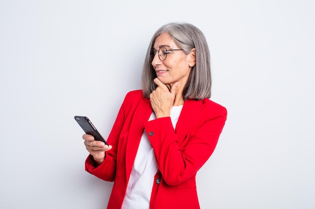 Senior mooie vrouw die lacht met een gelukkige, zelfverzekerde uitdrukking met de hand op de kin... zakelijke en telefoon concept