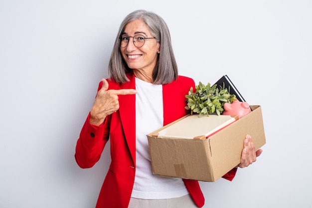 Senior mooie vrouw die vrolijk lacht, zich gelukkig voelt en naar de zijkant wijst. ontslag concept