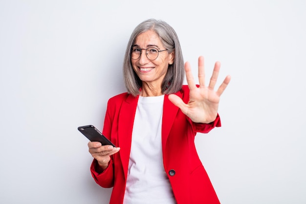 Senior mooie vrouw glimlacht en ziet er vriendelijk uit, met nummer vijf... bedrijfs- en telefoonconcept