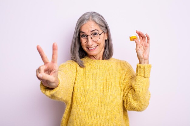 Senior mooie vrouw lacht en ziet er gelukkig uit, gebarend overwinning of vrede. contactlens concept