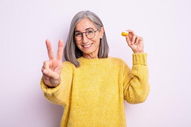 Senior mooie vrouw lacht en ziet er vriendelijk uit, met nummer twee. contactlens concept