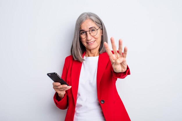 senior mooie vrouw lacht en ziet er vriendelijk uit, met nummer vier... bedrijfs- en telefoonconcept