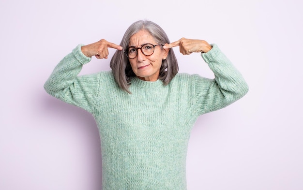 Senior mooie vrouw met een serieuze en geconcentreerde blik, brainstormend en nadenkend over een uitdagend probleem