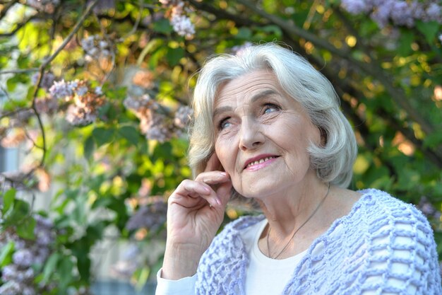 Senior mooie vrouw poseren met seringen in park