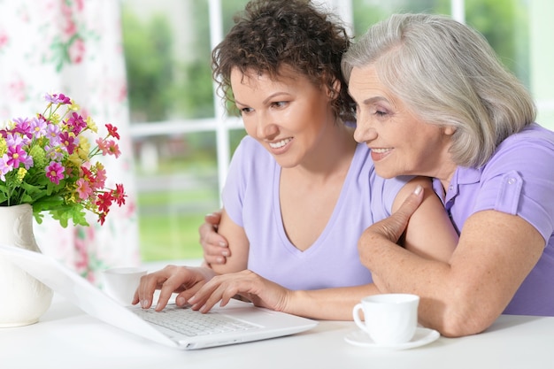 Senior mother and adult daughter working with laptop together