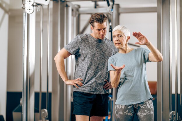 A senior mother and her middle age son talking before have a workout in a gym.