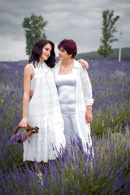 Senior mother with adult daughter walking on the lavender field