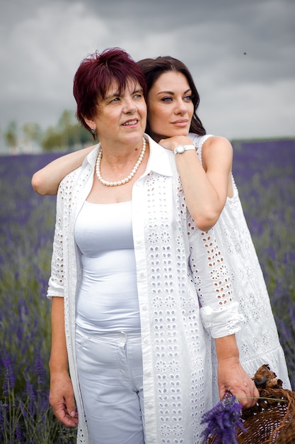 Senior mother with adult daughter walking on the lavender field