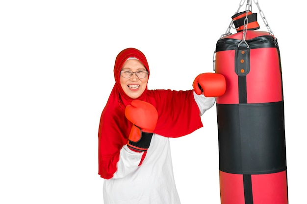 Пожилая мусульманка тренируется с боксерскими мешками