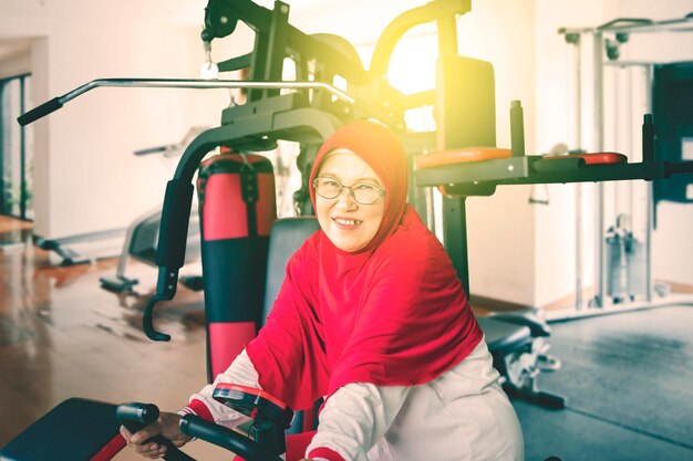 Senior muslim woman riding exercise bike in fitness center