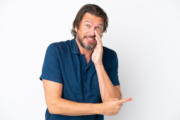 Senior Nederlandse man geïsoleerd op een witte achtergrond die naar de zijkant wijst om een product te presenteren en iets te fluisteren