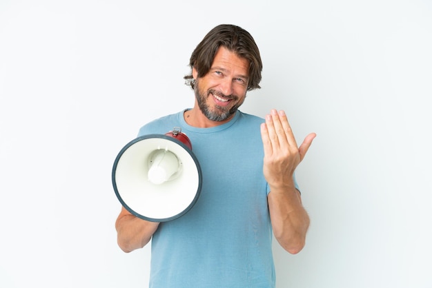 Senior Nederlandse man geïsoleerd op een witte achtergrond met een megafoon en uitnodigend om met de hand te komen