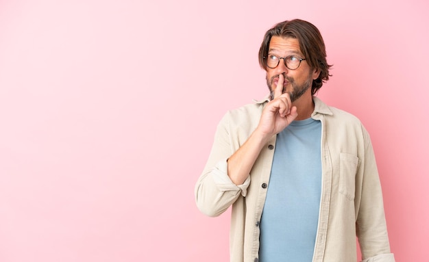 Senior Nederlandse man geïsoleerd op roze achtergrond met een teken van stilte gebaar vinger in mond