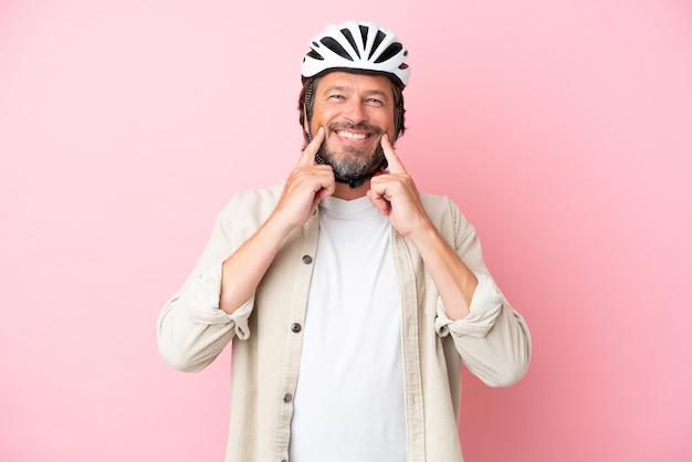 Senior Nederlandse man met fietshelm geïsoleerd op roze achtergrond glimlachend met een vrolijke en aangename uitdrukking