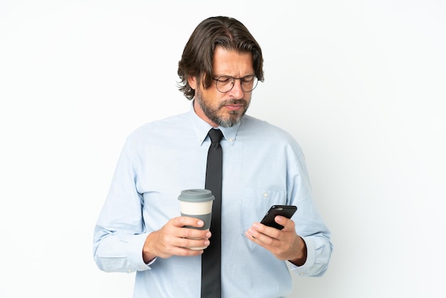 Senior Nederlandse zakenman geïsoleerd op een witte achtergrond met koffie om mee te nemen en een mobiel