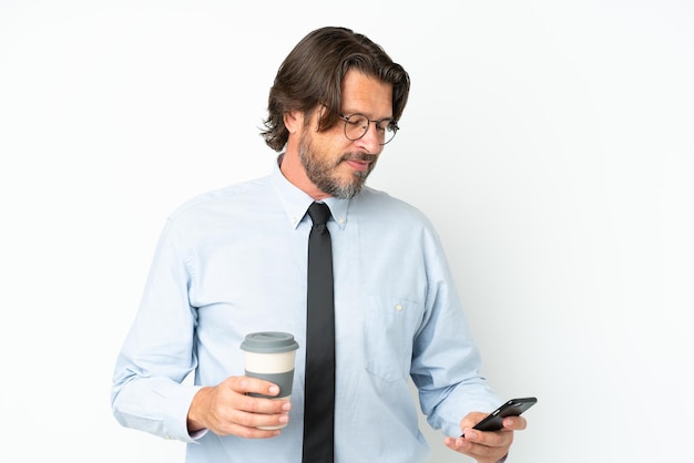 Senior Nederlandse zakenman geïsoleerd op een witte achtergrond met koffie om mee te nemen en een mobiel