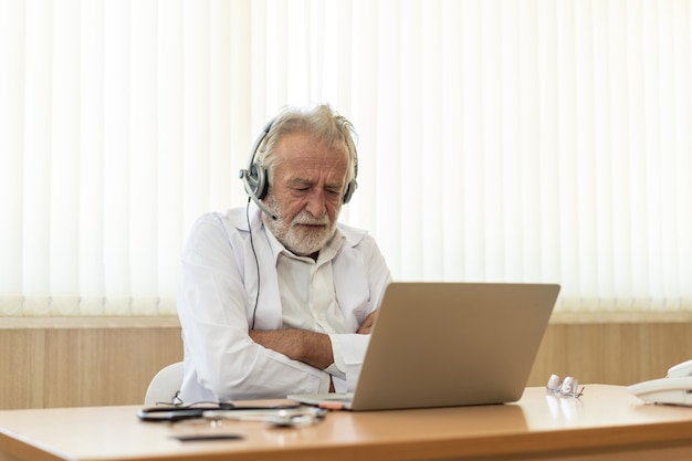 Senior old doctor wears headset  Remote online medical chat consultation, Telehealth concept