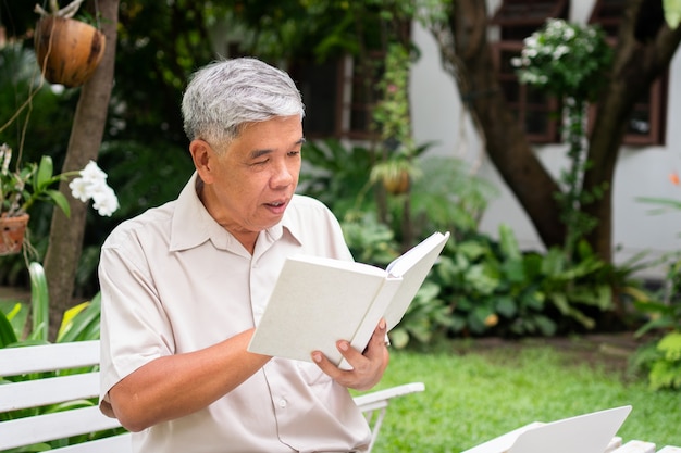 Senior oude man leest een boek in het park. Concept van pensioen levensstijl en hobby.