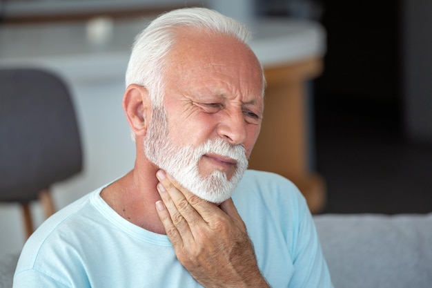 Senior oudere man die zijn nek aanraakt en lijdt aan nekpijn ischias sedentaire levensstijl concept nek gezondheidsproblemen Zorgverzekering