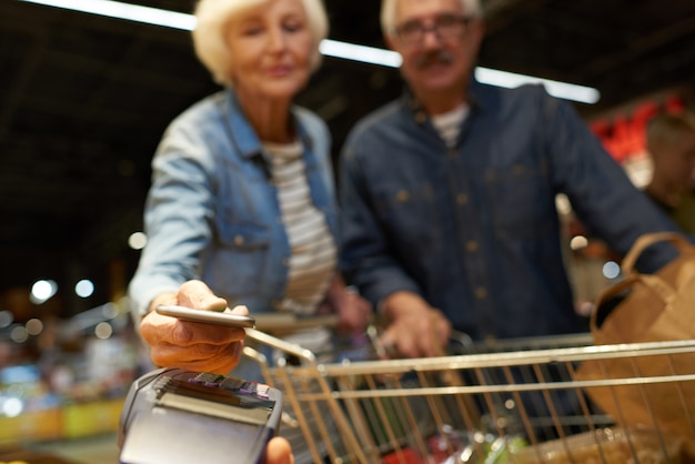 Senior paar betalen met mobiele telefoon