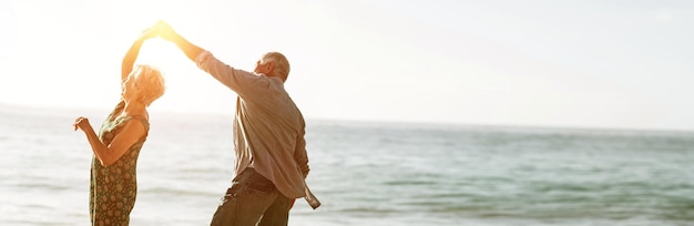 Senior paar dansen op het strand op zonnige dag