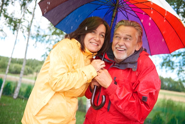 Senior paar delen een paraplu in de regen