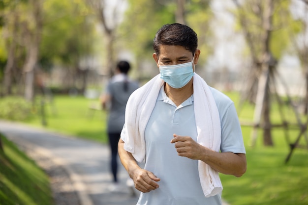 Senior paar dragen gezichtsmasker en wandelen via natuurpark, zomer buiten training